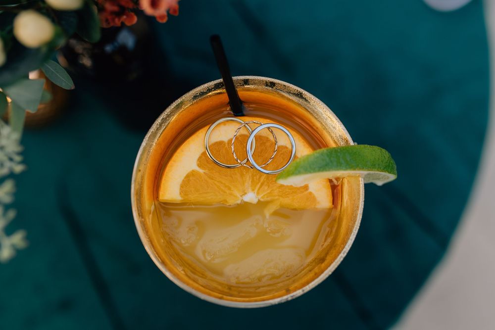 Top view of a citrus cocktail with wedding rings resting on an orange slice garnish.