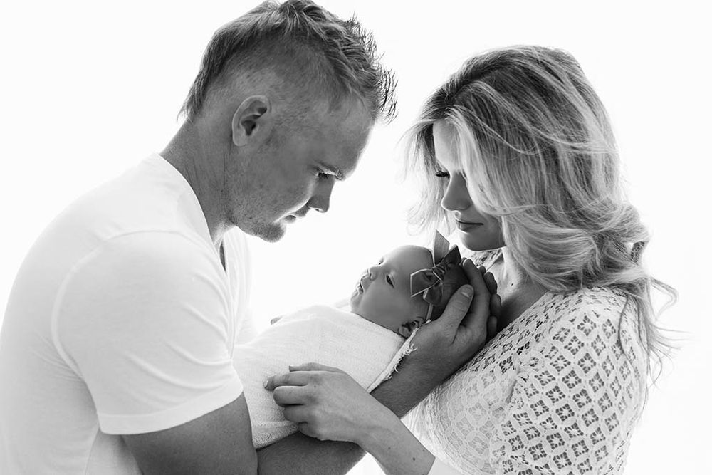 Winchester baby photographer black and white photo of parents lovingly gazing at their newborn baby in a bright photography studio.
