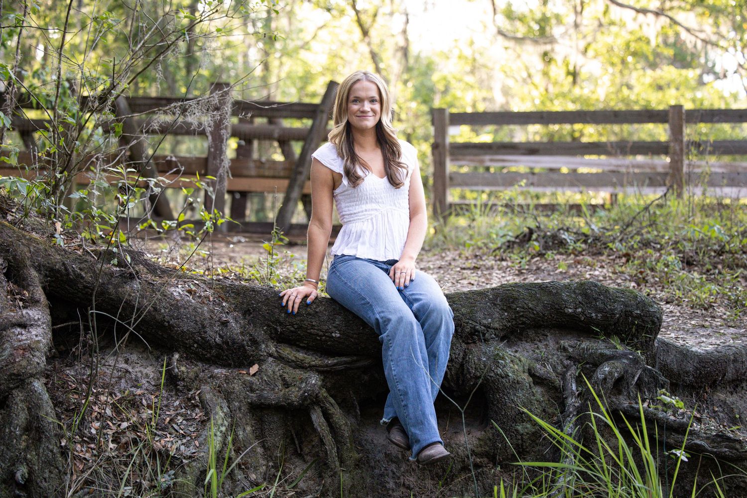 Large multigenerational family portrait on a wooden bridge surrounded by lush trees in a natural outdoor setting.