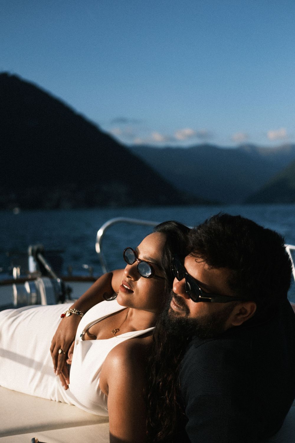 Engagement portrait of couple laying down in each others arms on private boat.