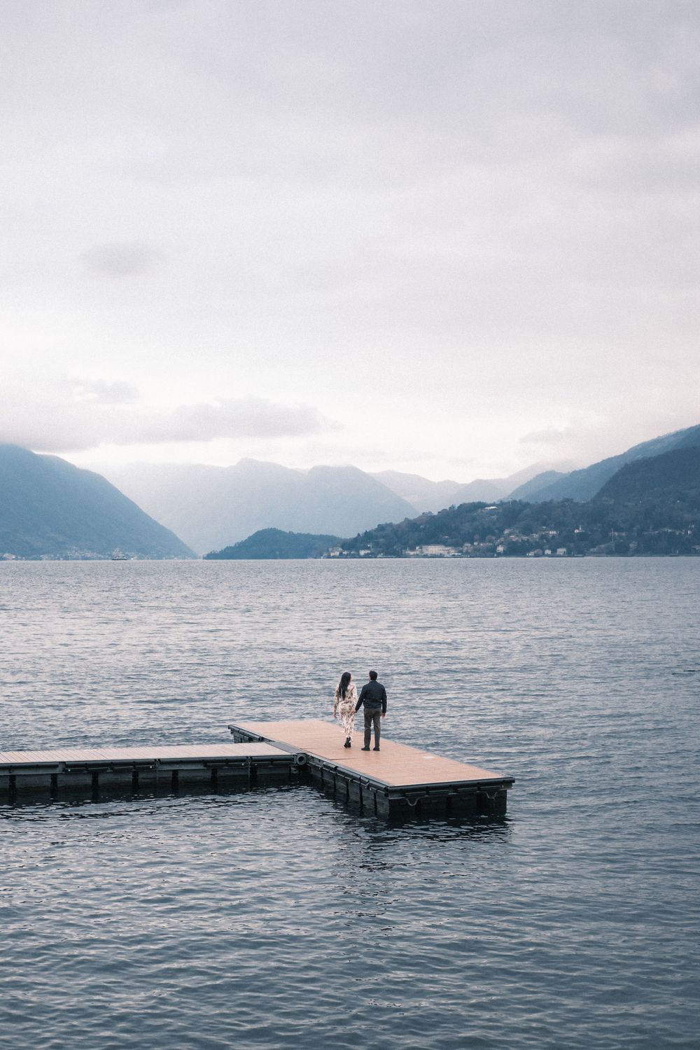 Distant view of figures standing on a floating dock in a mountain lake.