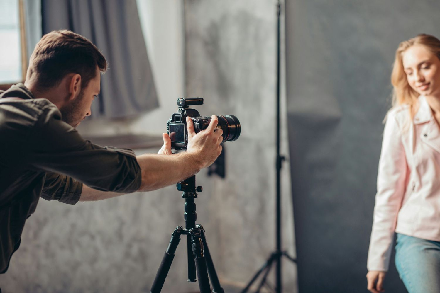 Photographer taking a headshot of a woman in a studio, highlighting the setup and professionalism of a dedicated photo session