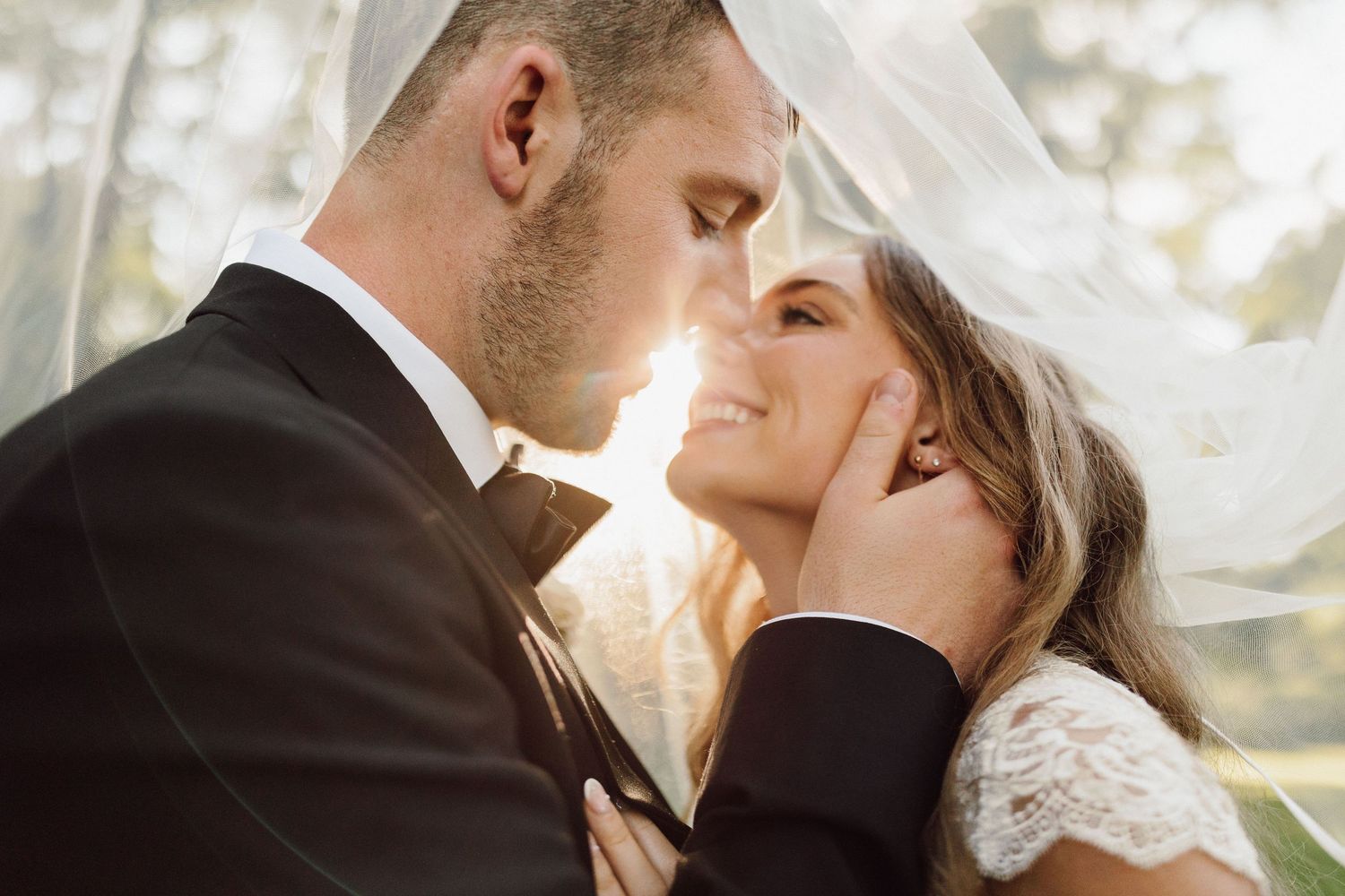 Romantic wedding portrait with couple sharing an intimate moment in golden sunlight.