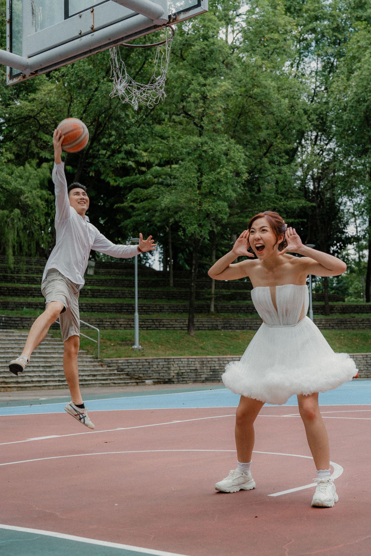 A joyful scene on a basketball court as two people play and laugh together.