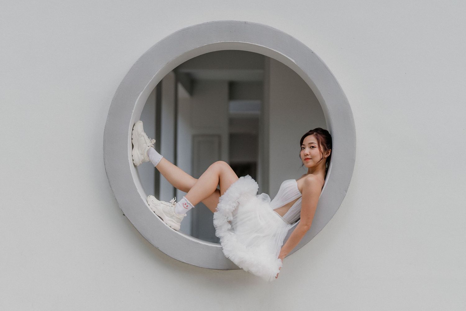 Artistic wedding photo through circular window frames showing bride in white dress.