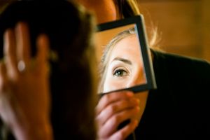A bride's eye is pictured reflected in a mirror as she gets ready for her wedding day in Vermont