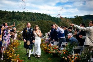 Wedding guests shower the couple with flower confetti as they walk back up the aisle in Vermont