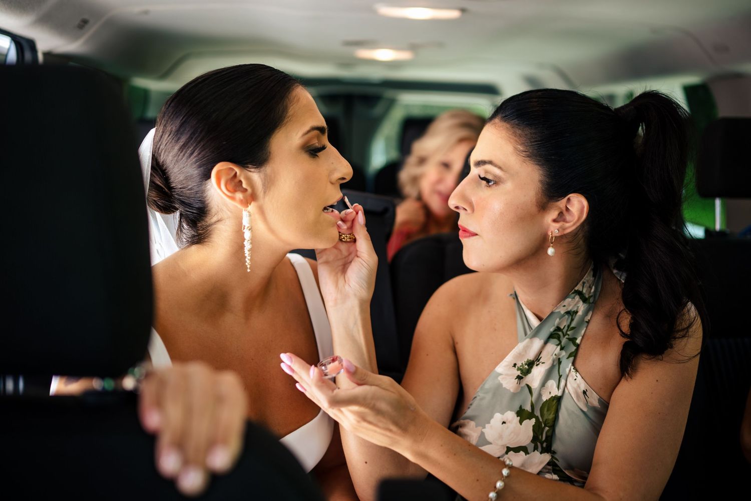 bride getting finishing touches of makeup on before arriving at the ceremony at The Old Gray Barn in Vermont