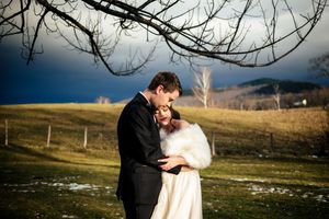 A wedding couple embraces in the wintry Vermont landscape at The Inn at the Round Barn Farm in Waitsfield, Vermont