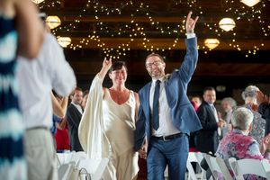 A wedding couple puts up the "rock on" hand signal together as they are introduced at their reception