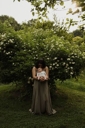 A dreamy garden portrait with flowering bushes framing figures in soft evening light.