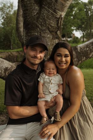 A heartwarming family portrait taken under a birch tree with natural lighting and soft earth tones.