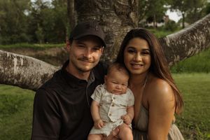 An intimate family portrait taken against the backdrop of a large birch tree in a park setting.