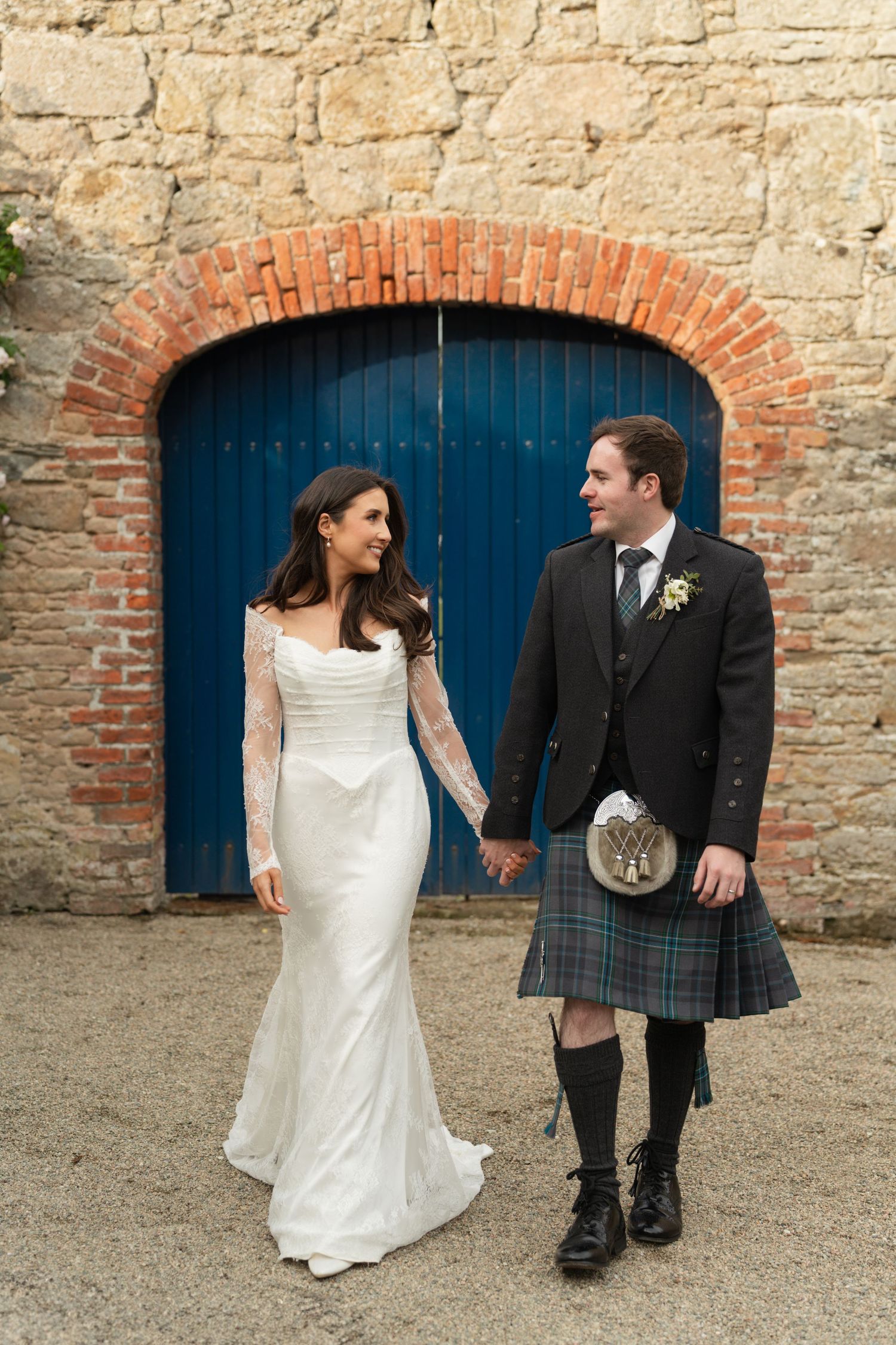 Against a rustic stone wall and blue doors, a couple in wedding attire poses together in five progressive shots.