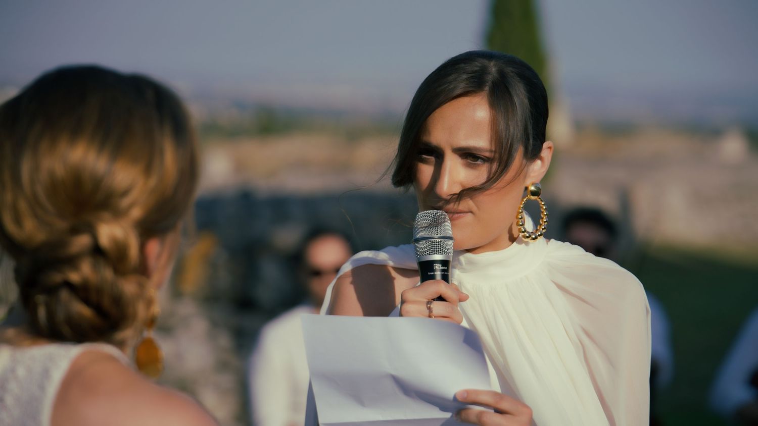 Wedding guests gather on a stone terrace with panoramic mountain views in the background.