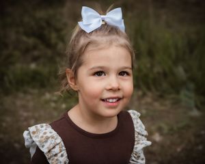 Collection of candid outdoor portraits showing joyful expressions and a white hair bow against a natural backdrop.