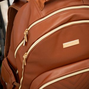 Close-up product shots showing brown leather backpack with gold zipper details and cream accents.