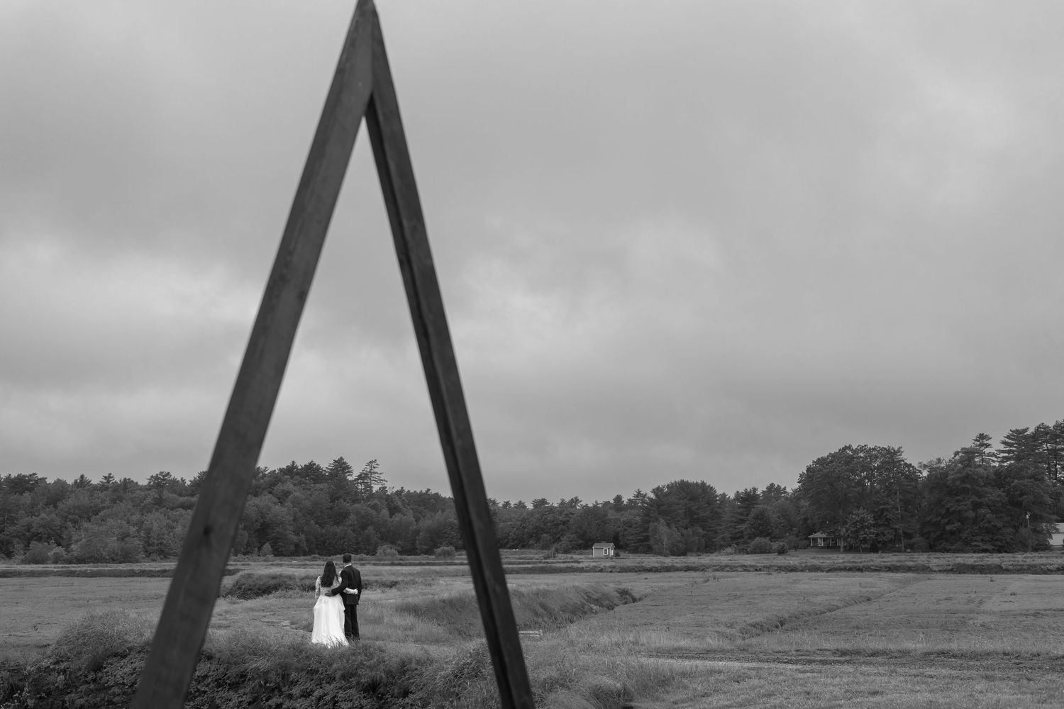 A panoramic sequence of black and white landscape photographs showing a triangular structure against a cloudy sky.