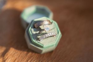 Wedding rings nestled in a mint green velvet hexagonal ring box with vintage styling.