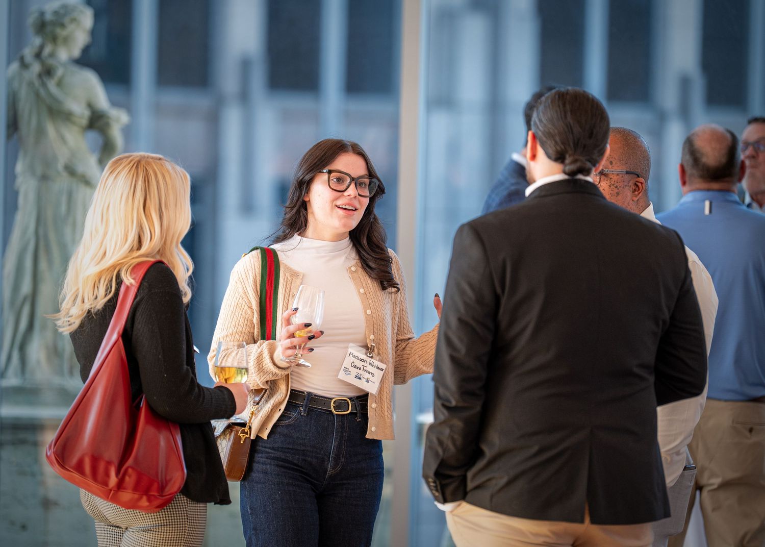 People engaged in casual conversation at networking event with classical decor.