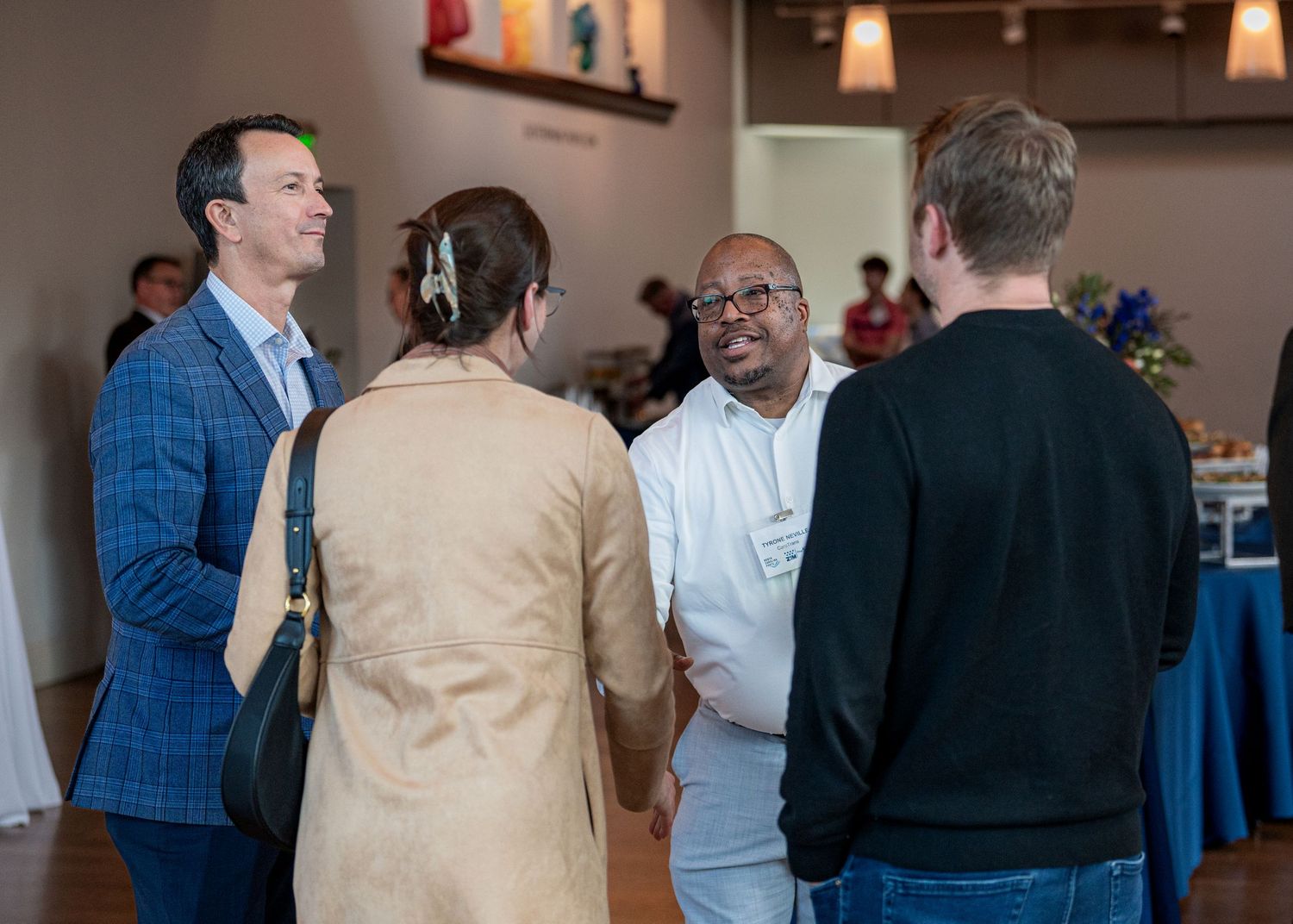 Small group of professionals engaged in networking conversation at indoor event.
