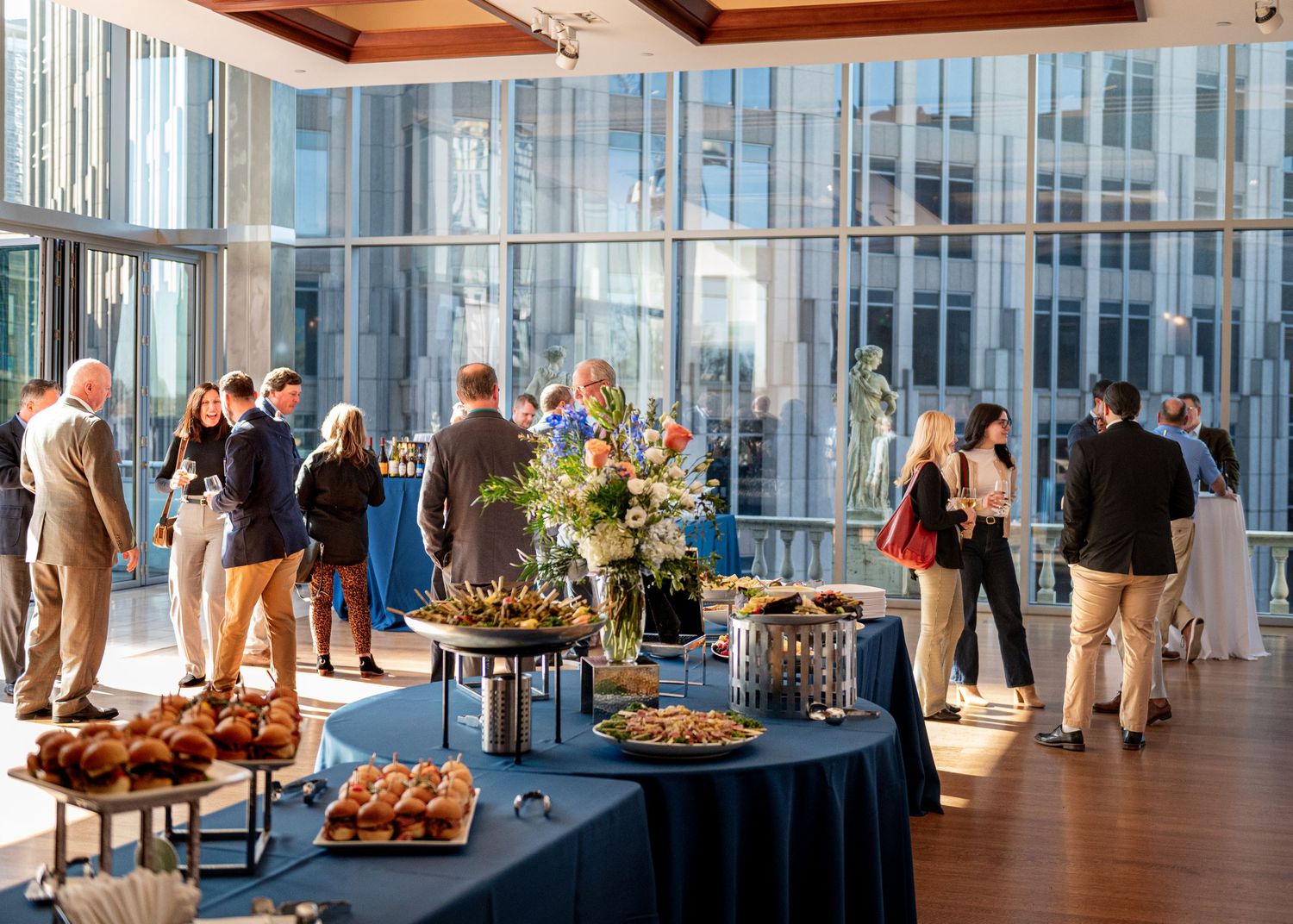 Large modern event space with buffet tables and attendees mingling during a corporate gathering.