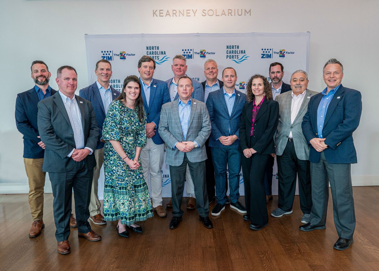 Business group poses for formal photo in front of Kearney Solarium sign.