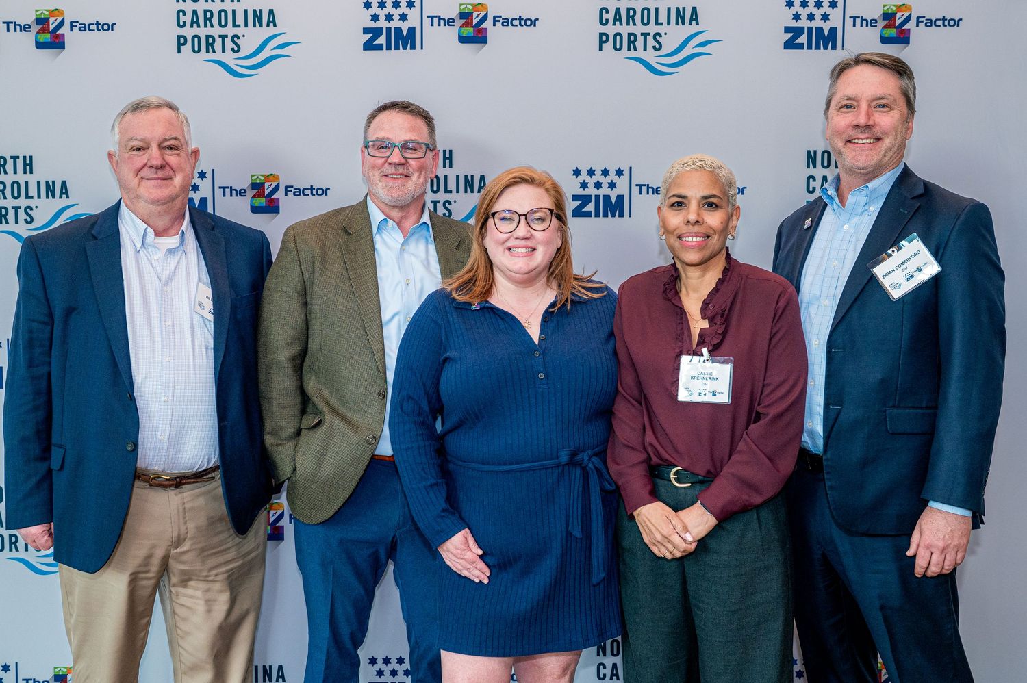 Professional group poses for photo at Carolina event with branded backdrop.