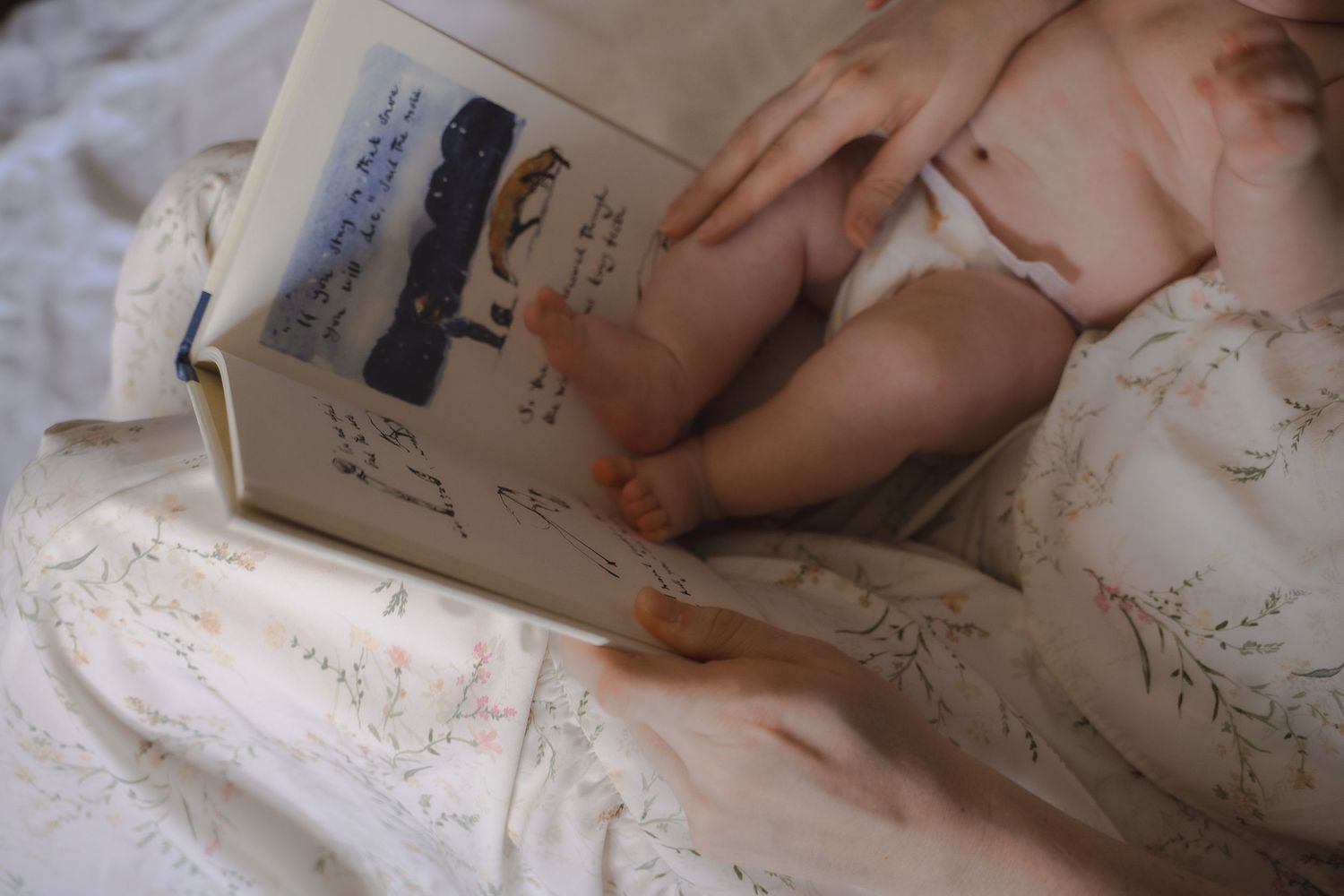 Tiny baby feet resting on a floral blanket as their mother reads a children’s book during a calm and cosy in-home family session in Leiceste