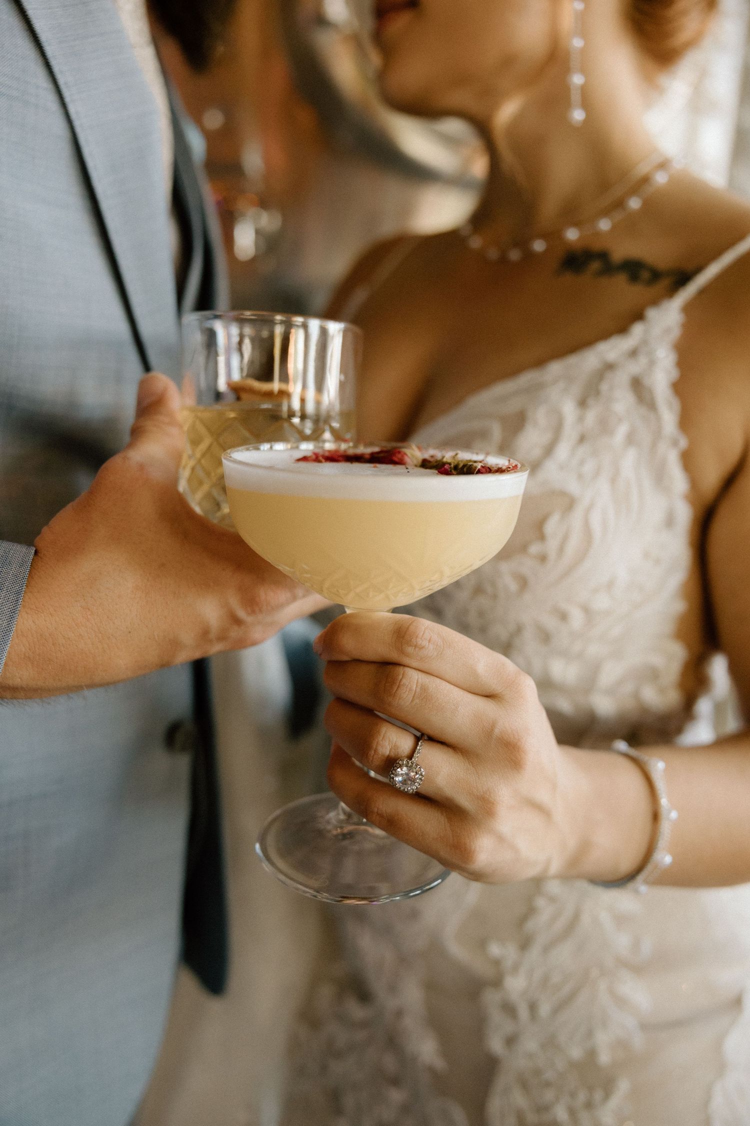 Close up of hands holding a champagne glass with delicate lace details visible on a white dress.