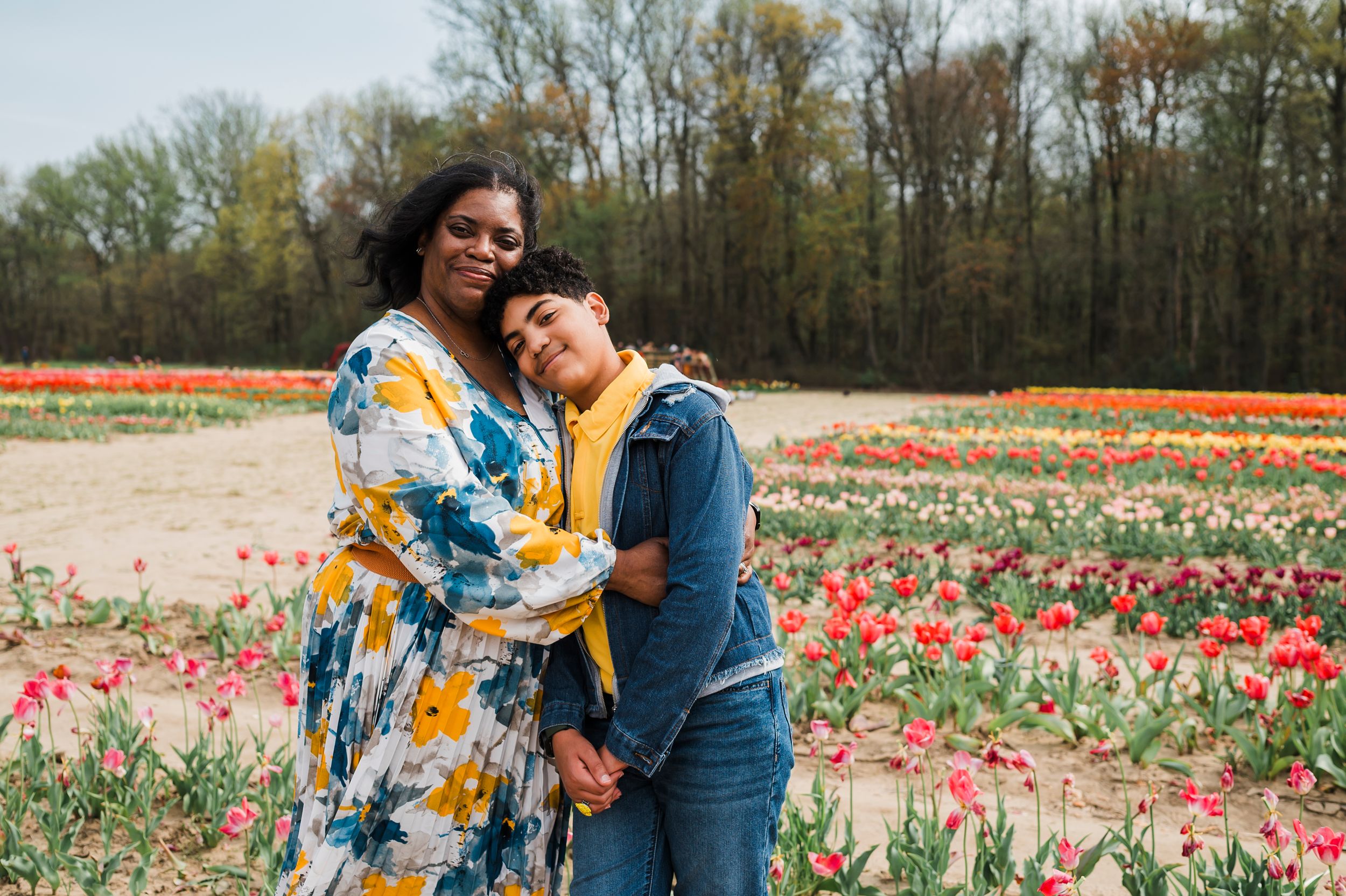 A couple stands together in a vibrant tulip field during spring surrounded by colorful blooming flowers.