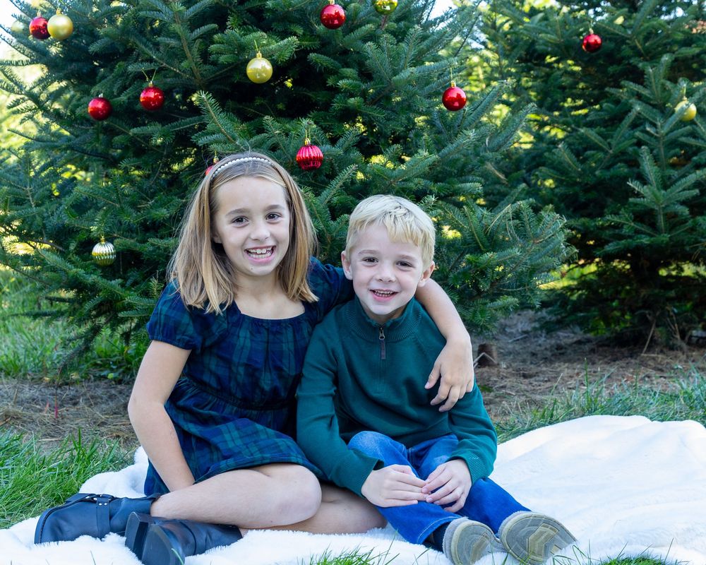 Siblings pose together at Mistletoe Christmas Tree Farm in Stow, MA at holiday photos by Lisa West Photography www.lisawestphotography.com
