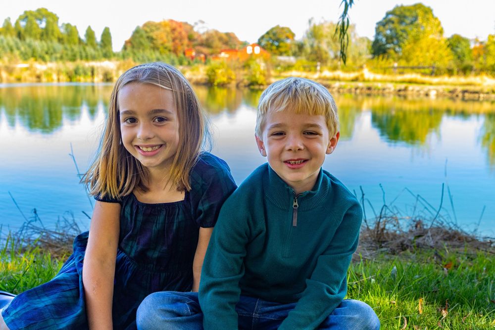 Siblings pose together by the pond at Mistletoe Christmas Tree Farm in Stow, MA for a holiday mini photo session by Lisa West Photography