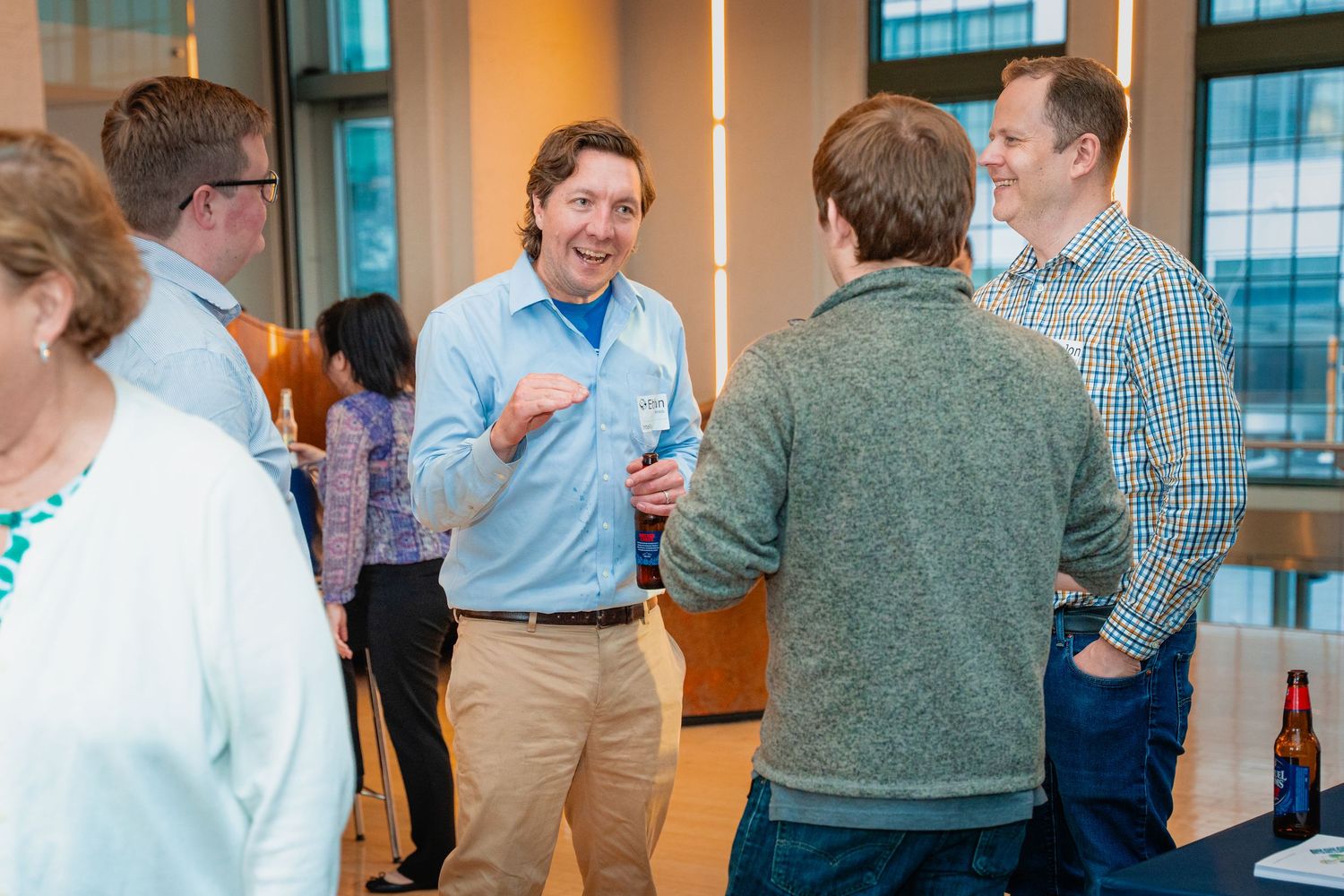 People networking and mingling at a professional business event in a bright modern office space.