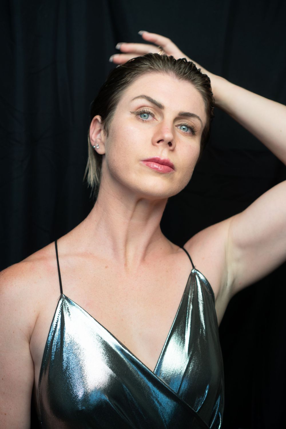 Portrait of person in metallic silver dress against dark background.