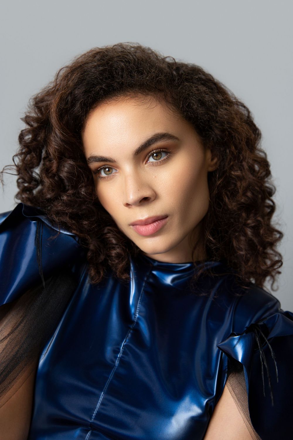 Studio beauty portrait featuring curly hair and blue metallic fashion top.
