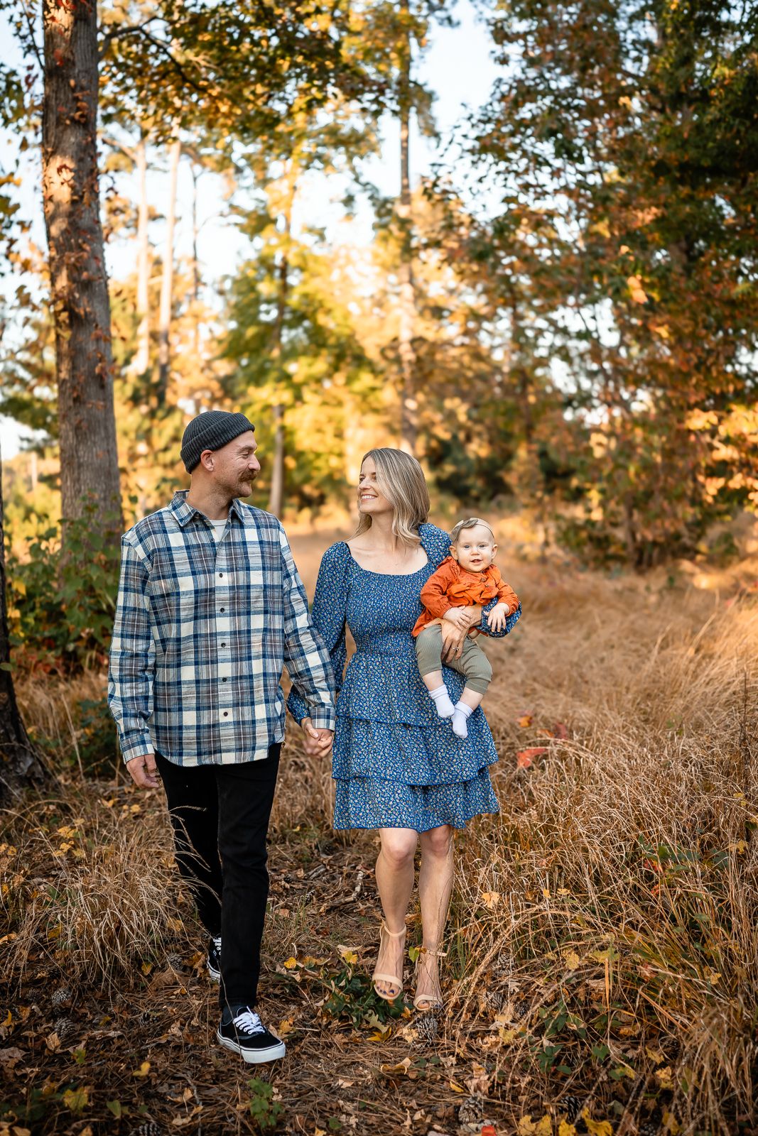 Family walking together through golden autumn forest at sunset.