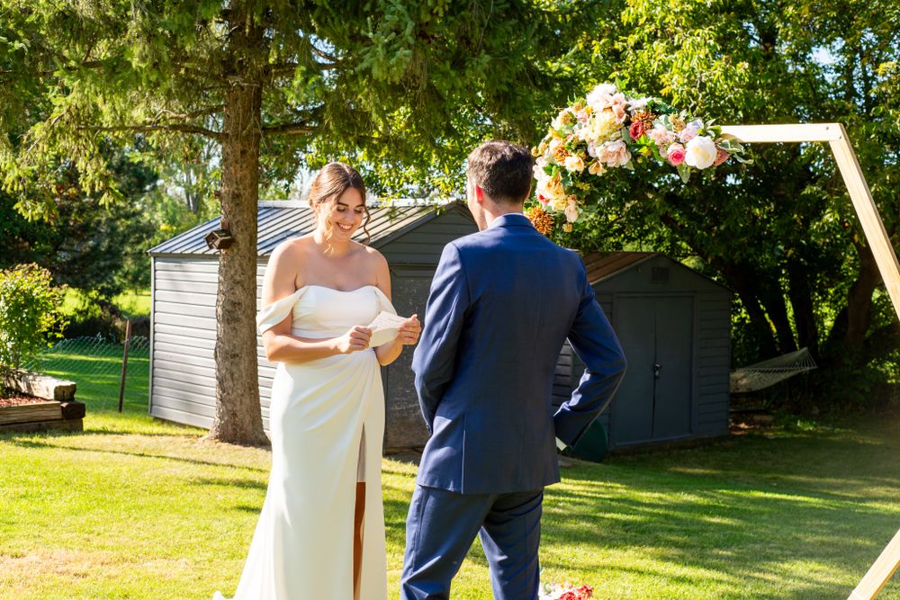 A sun-drenched outdoor wedding ceremony with a hexagonal floral arch.