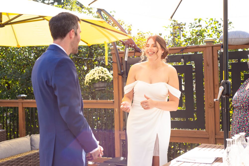 A sunny outdoor wedding ceremony moment under a yellow patio umbrella.