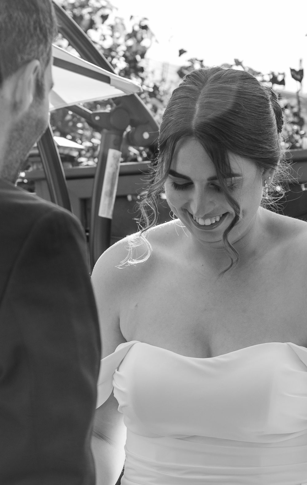 Black and white closeup of bride smiling during outdoor ceremony.