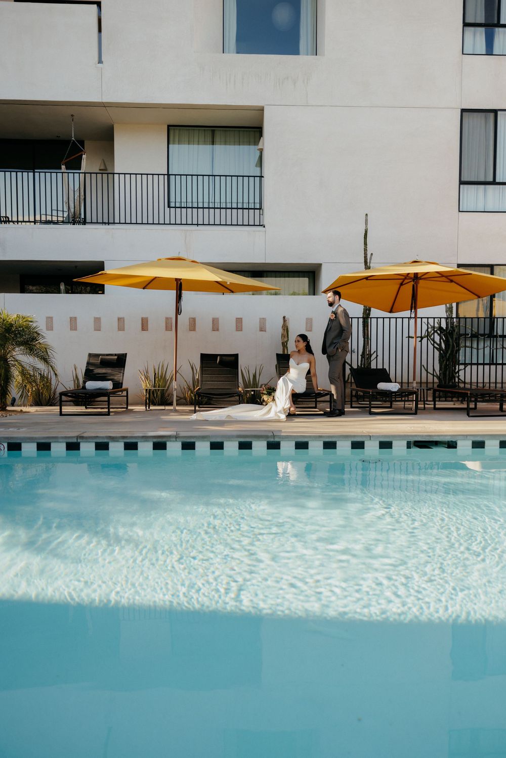 A stunning poolside setting with turquoise water and yellow umbrellas at a modern hotel on a sunny day.