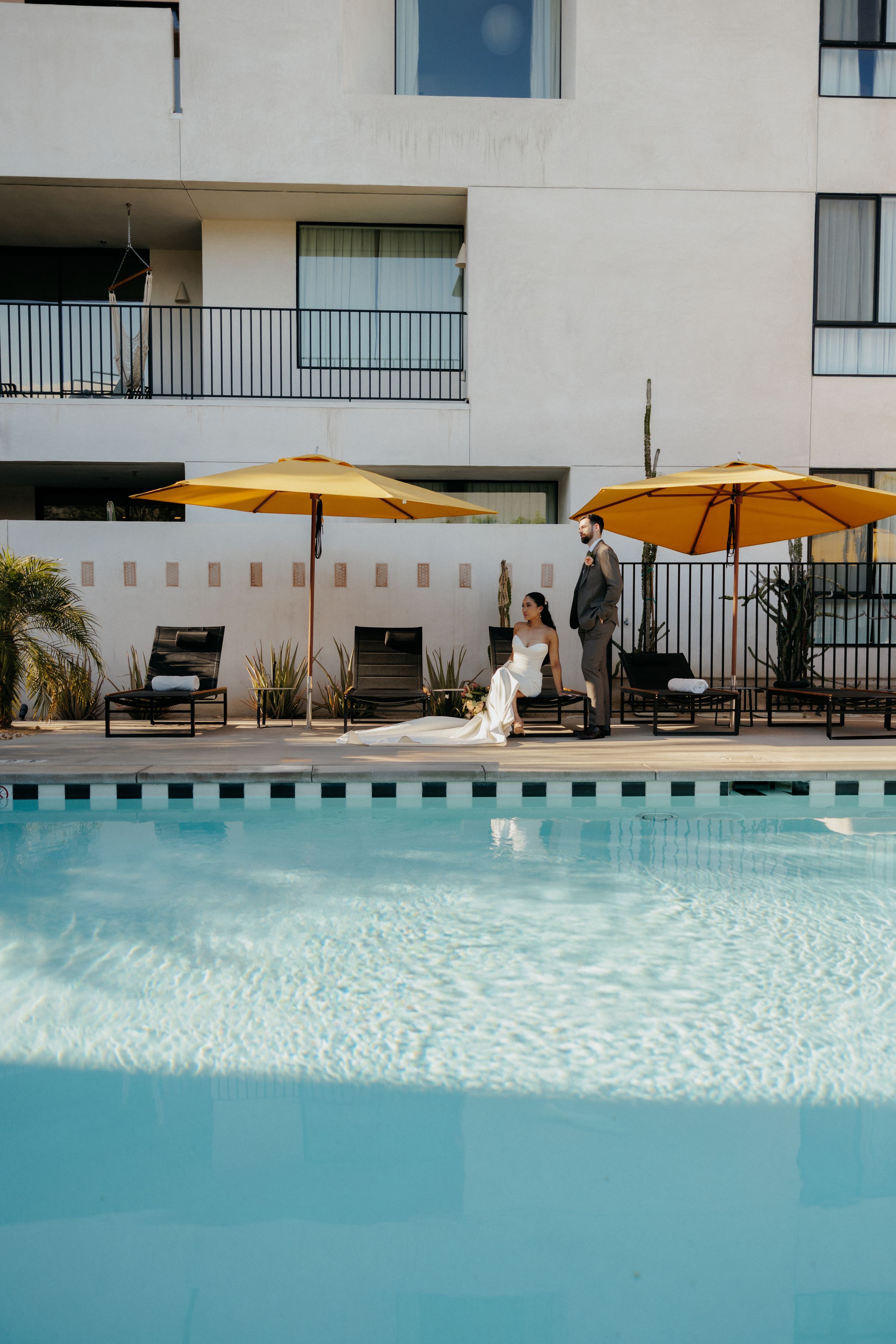 A stunning poolside setting with turquoise water and yellow umbrellas at a modern hotel on a sunny day.