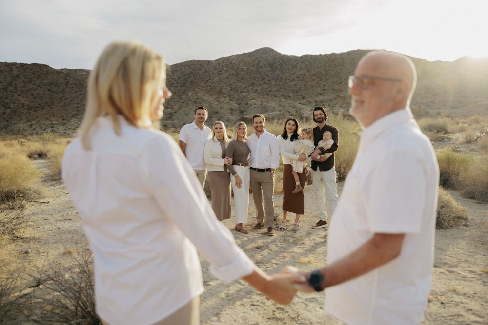 A small intimate desert wedding ceremony during sunset with attendees wearing white and earth-toned clothing.