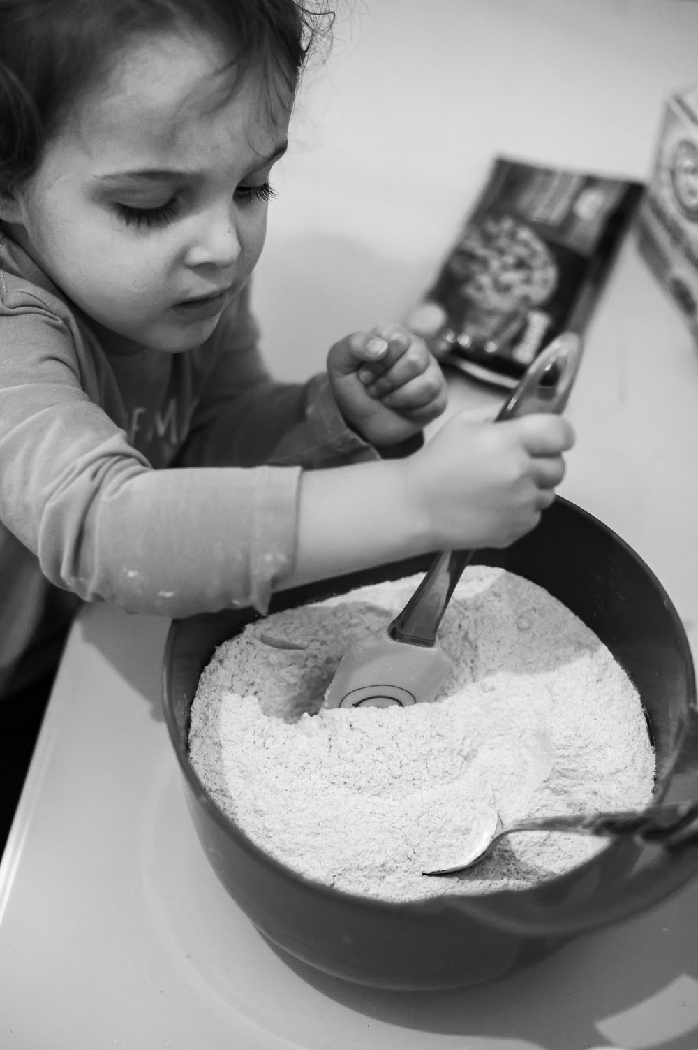 Child stirring ingredients in mixing bowl during baking activity.