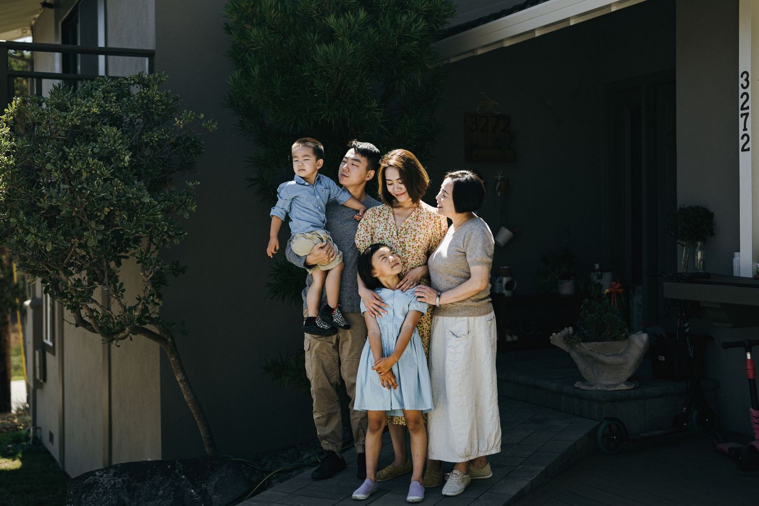 A family group standing together outside their home in evening light.