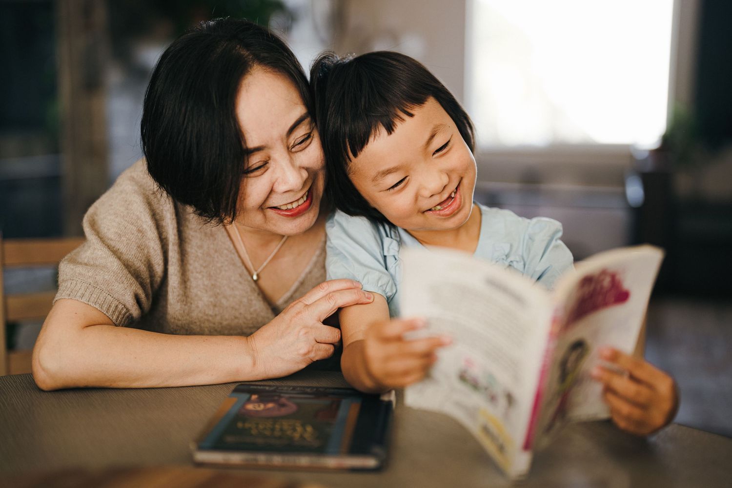 A heartwarming moment of reading together at a table with books.