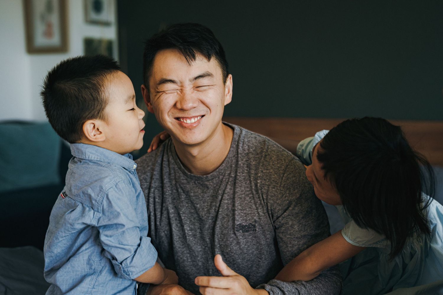 A joyful family moment shared on a dark couch in a living room setting.
