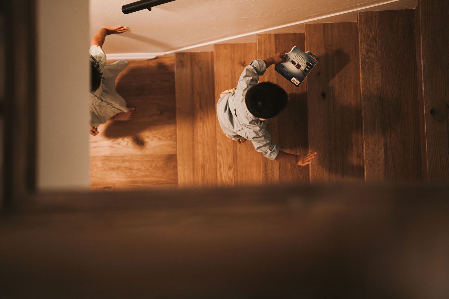 An overhead view of someone lying on wooden flooring in dramatic lighting.