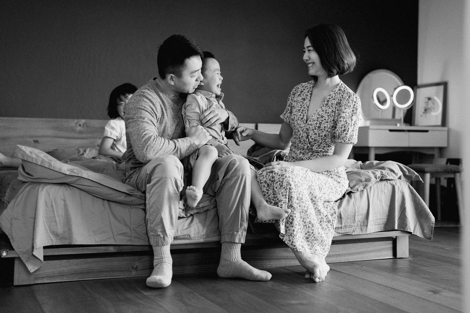 A family sitting together on a gray couch in a minimalist room setting.