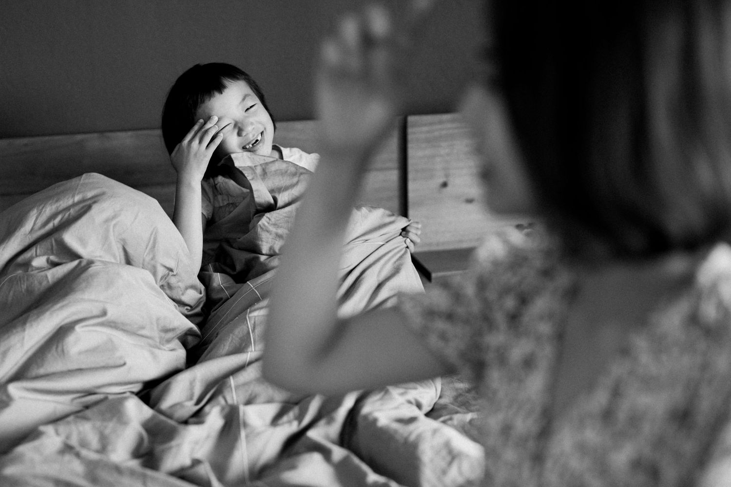 Someone reading a book in bed with dramatic lighting and shadows.